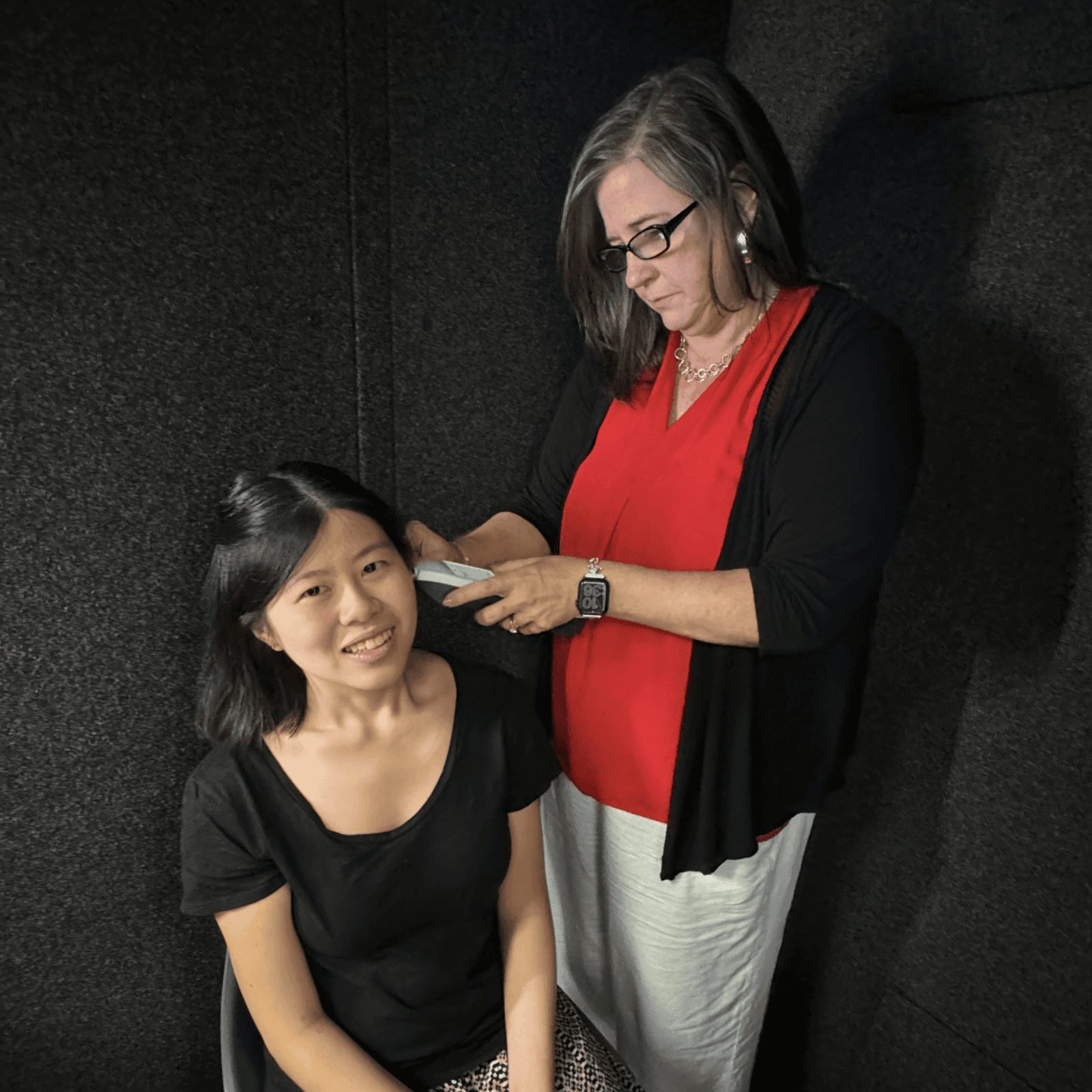 Dr. Sanders fitting headphones on a patient in the sound booth
